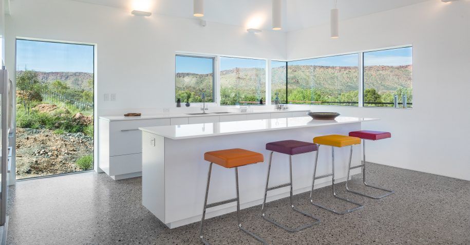 A kitchen with a large island and colorful stools