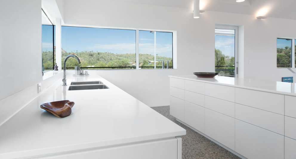 A kitchen with white cabinets , a sink , and a large window.