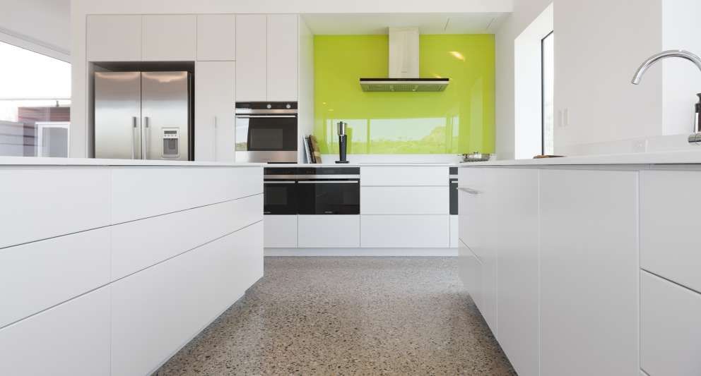 A kitchen with white cabinets and a green wall.