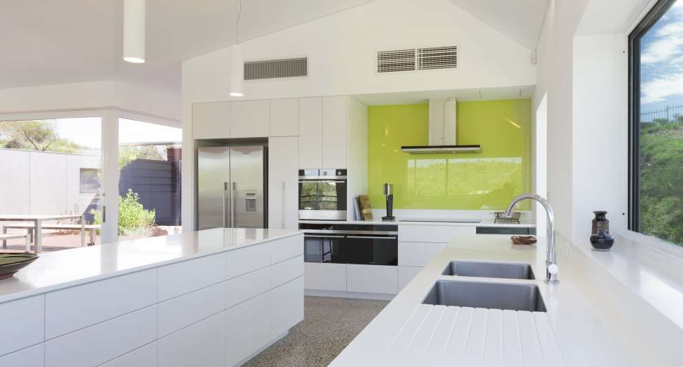 A kitchen with white cabinets and a green wall