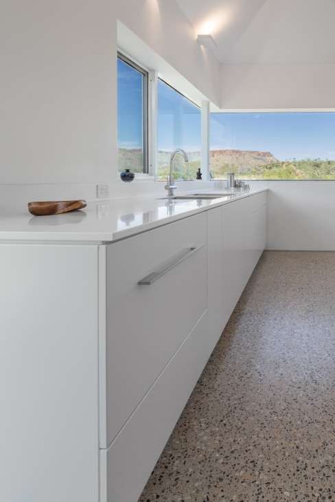 A kitchen with white cabinets , a sink , and a large window.