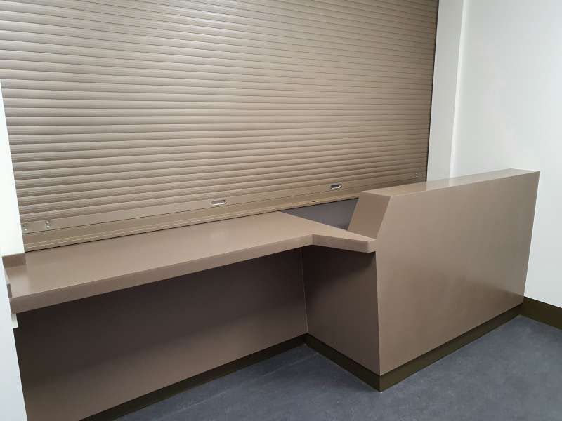 An empty room with a counter and a shutter on the wall