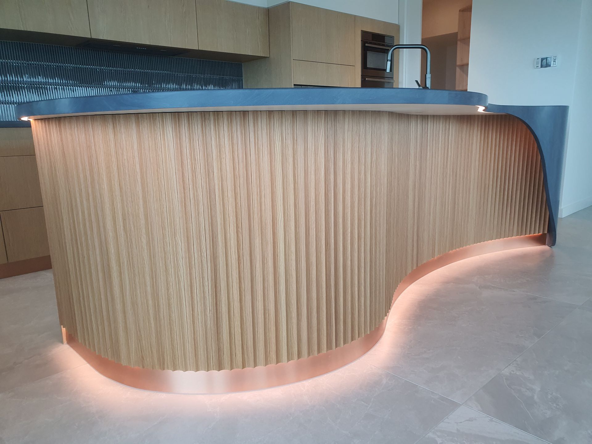A kitchen with a curved wooden counter top and copper trim.
