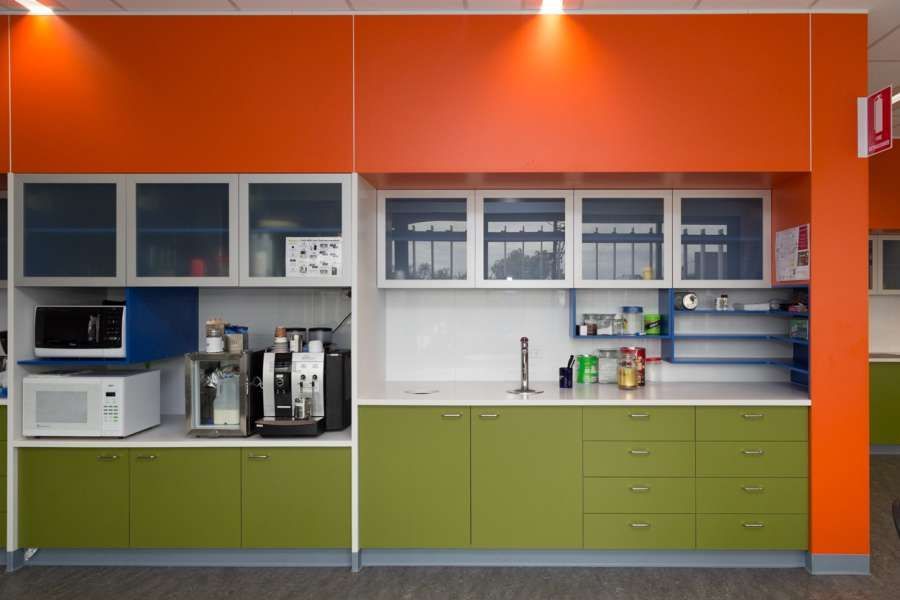 A kitchen with green cabinets and orange walls