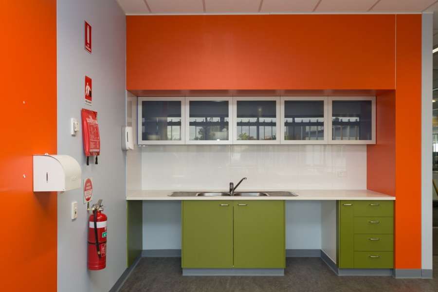 A kitchen with green cabinets and orange walls.