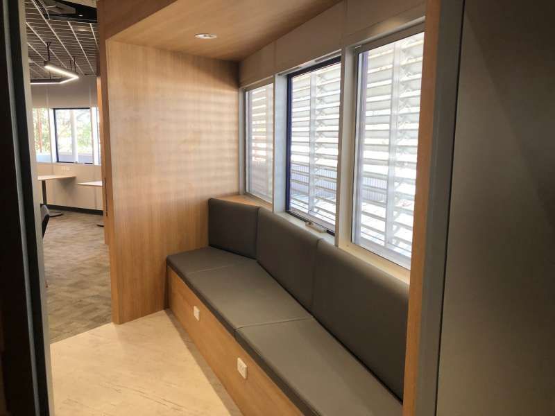 There is a bench in the corner of the room with a lot of windows.