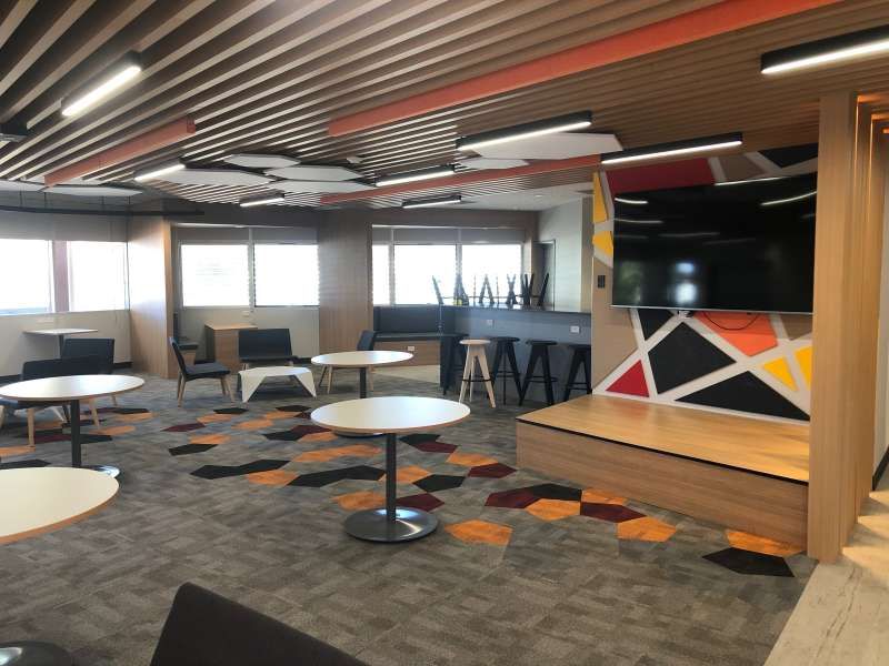 A large room with tables and chairs and a flat screen tv