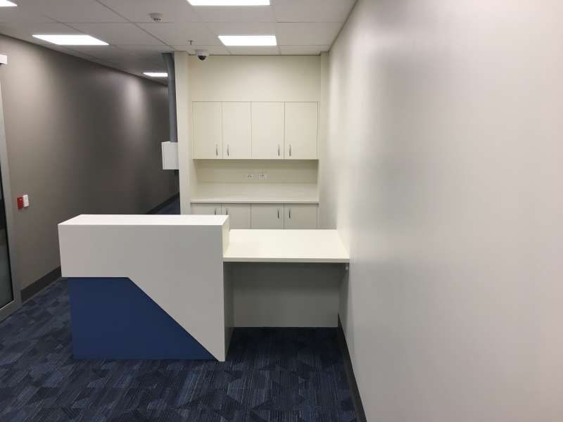 An empty office with a blue and white counter and cabinets