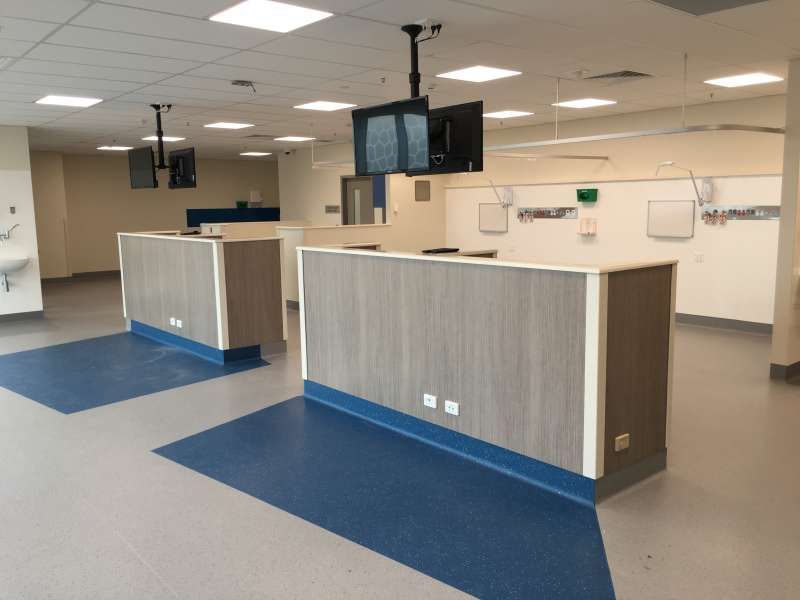 An empty hospital room with a ceiling mounted tv