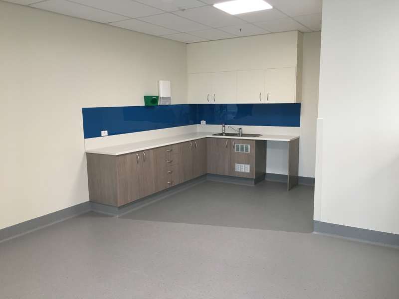 A kitchen with a sink , cabinets , and a blue wall.
