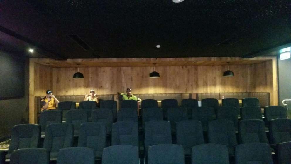 A row of empty seats in a theater with a wooden wall.