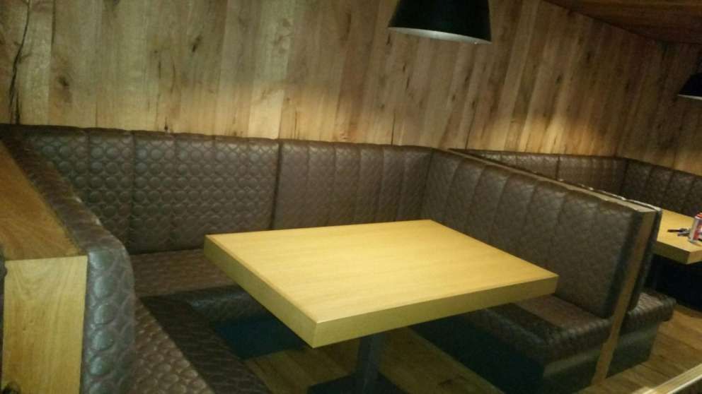 A wooden table is sitting in a booth in a restaurant.