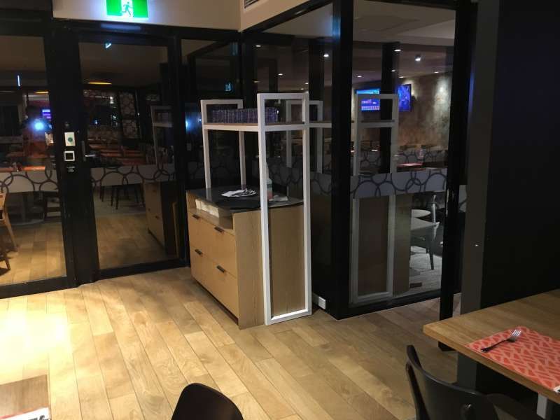 A restaurant with tables , chairs , and a large glass door.
