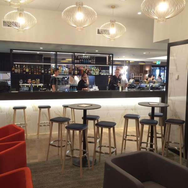 A restaurant with tables and stools in front of a bar