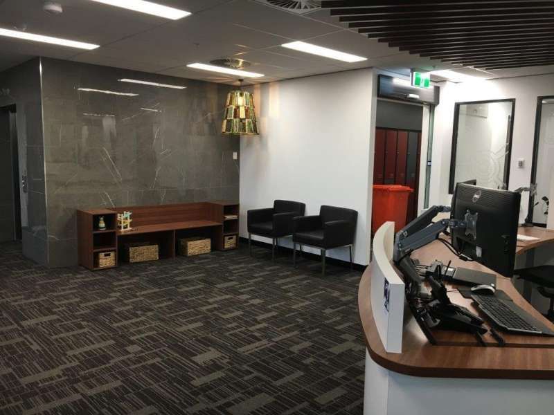 A waiting room with a desk , chairs and a computer.