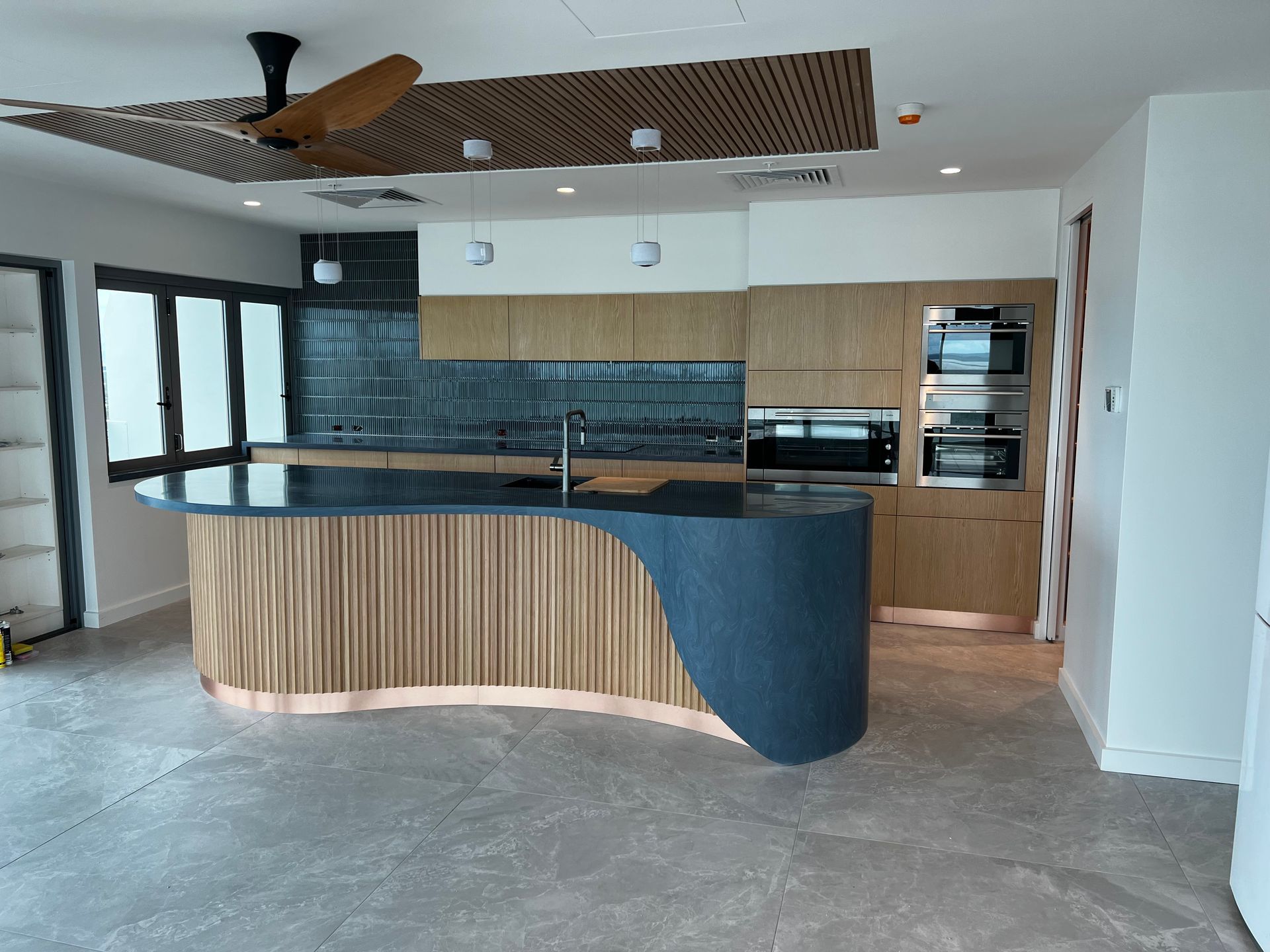 A kitchen with a large island and a ceiling fan.