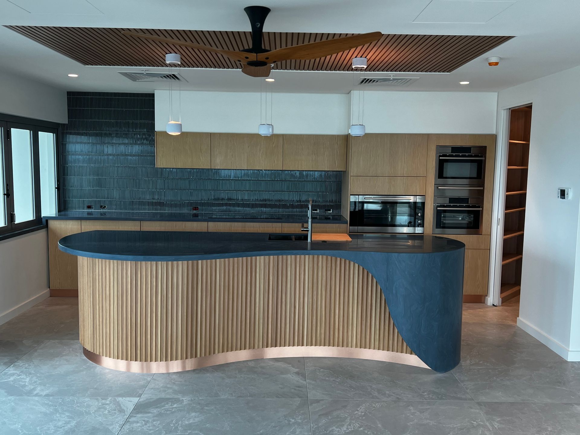 A kitchen with a large island and a ceiling fan.