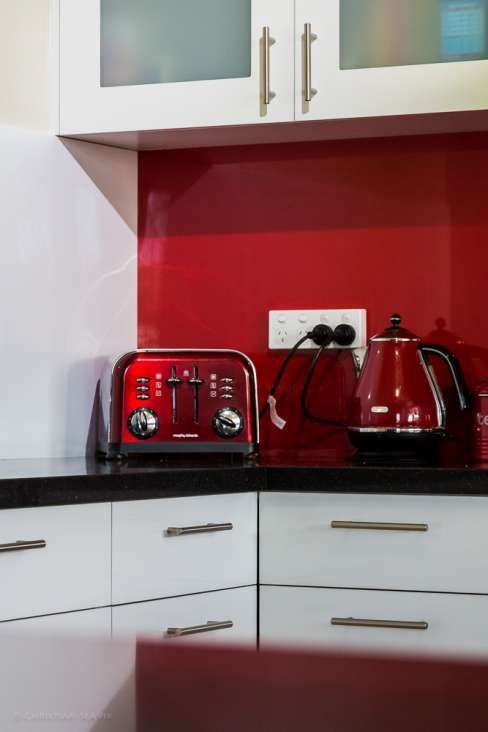 A kitchen with a red toaster and a red kettle