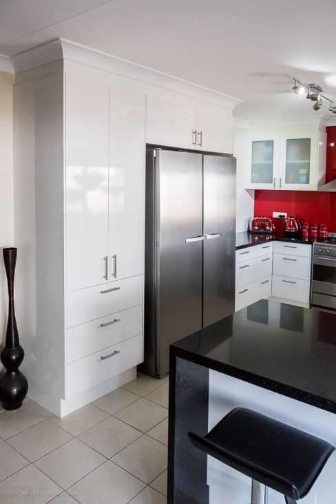 A kitchen with white cabinets and a stainless steel refrigerator