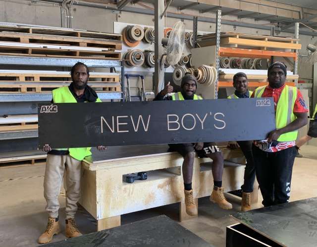 A group of men are holding a sign that says new boy 's