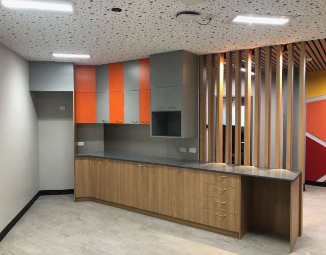 A kitchen with orange and gray cabinets and a wooden divider.