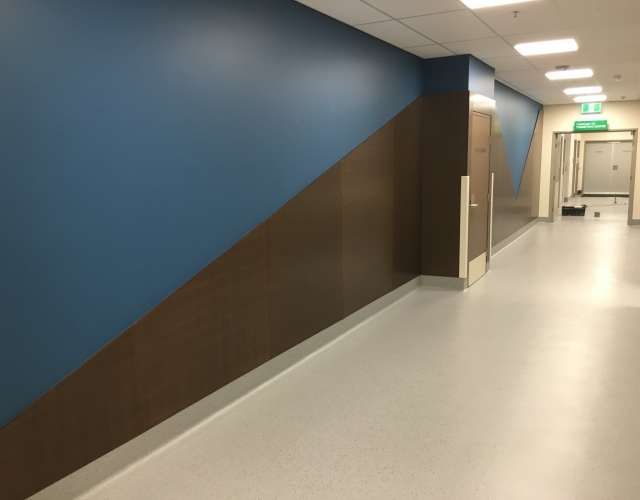 A hallway with blue and brown walls and a green exit sign