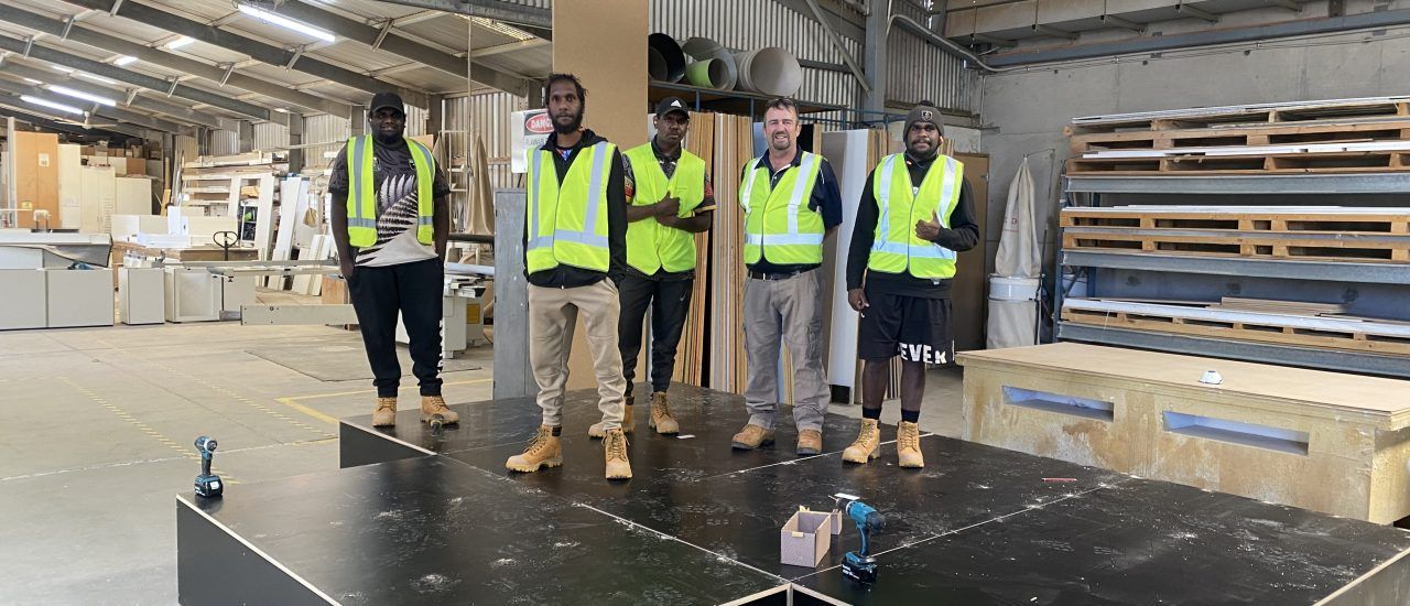 A group of men are standing next to each other in a warehouse.