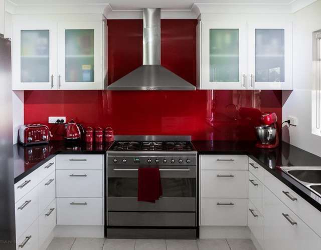 A kitchen with red walls and white cabinets