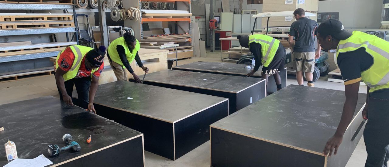 A group of men are working on a table in a factory.