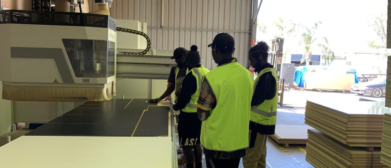A group of people are standing in front of a machine in a factory.