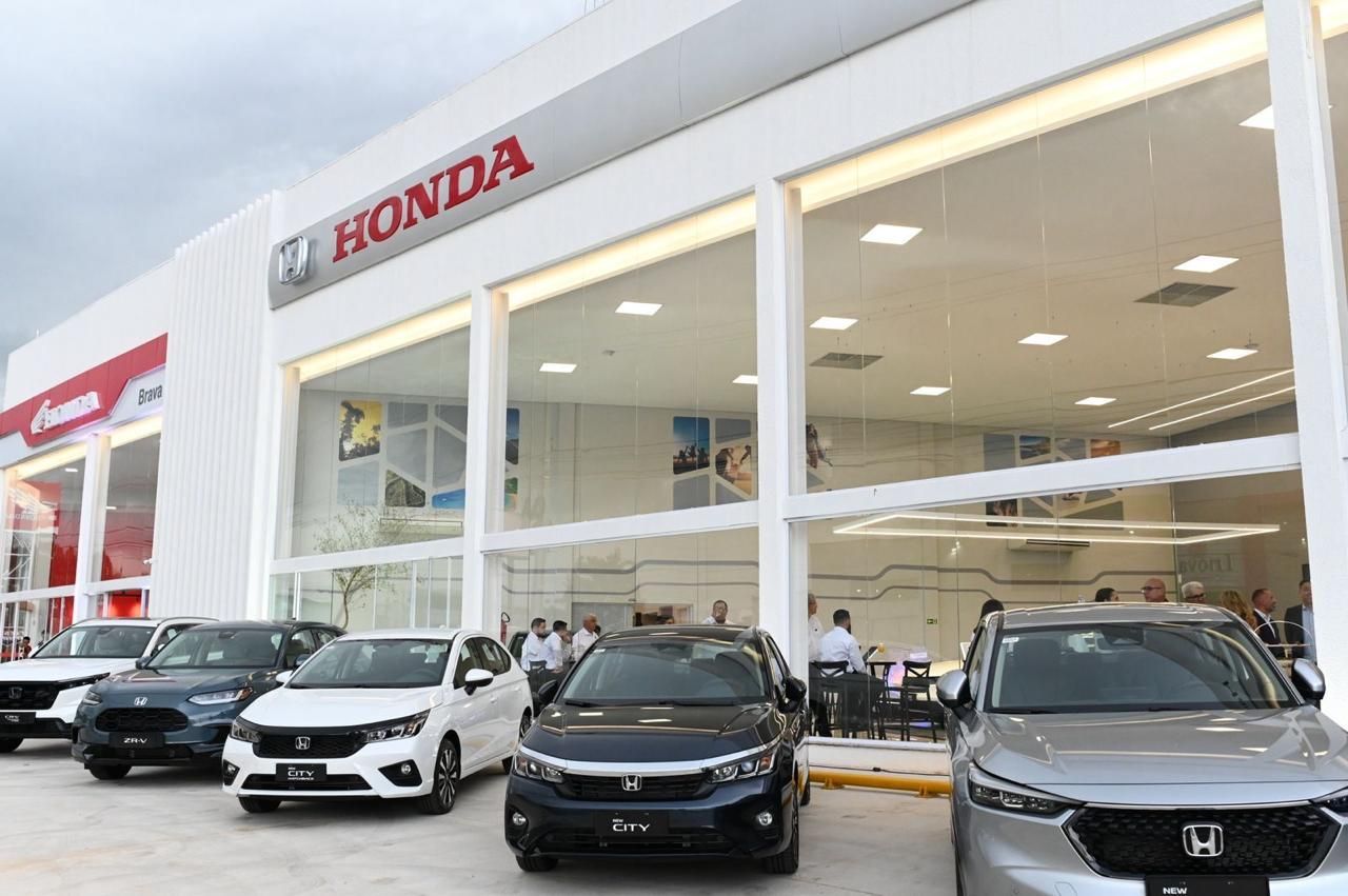 Honda dealership showroom with several cars displayed inside and outside the glass-front entrance
