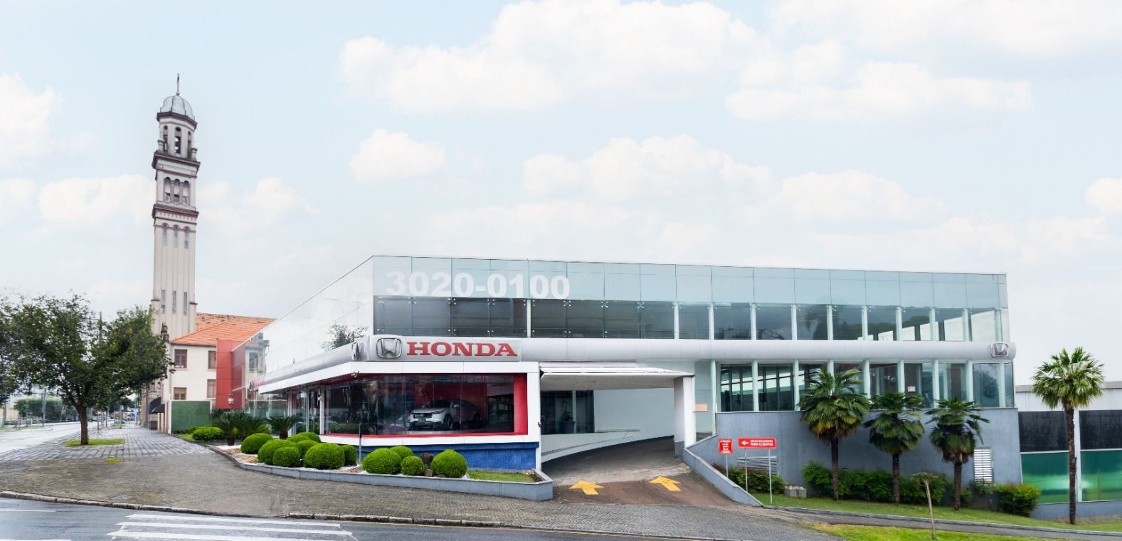 Honda car dealership building with tall sign, white facade, and blue sky