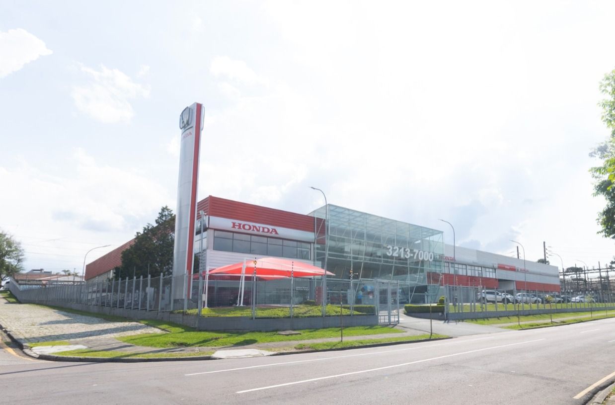 Honda car dealership building with tall sign, white facade, and blue sky