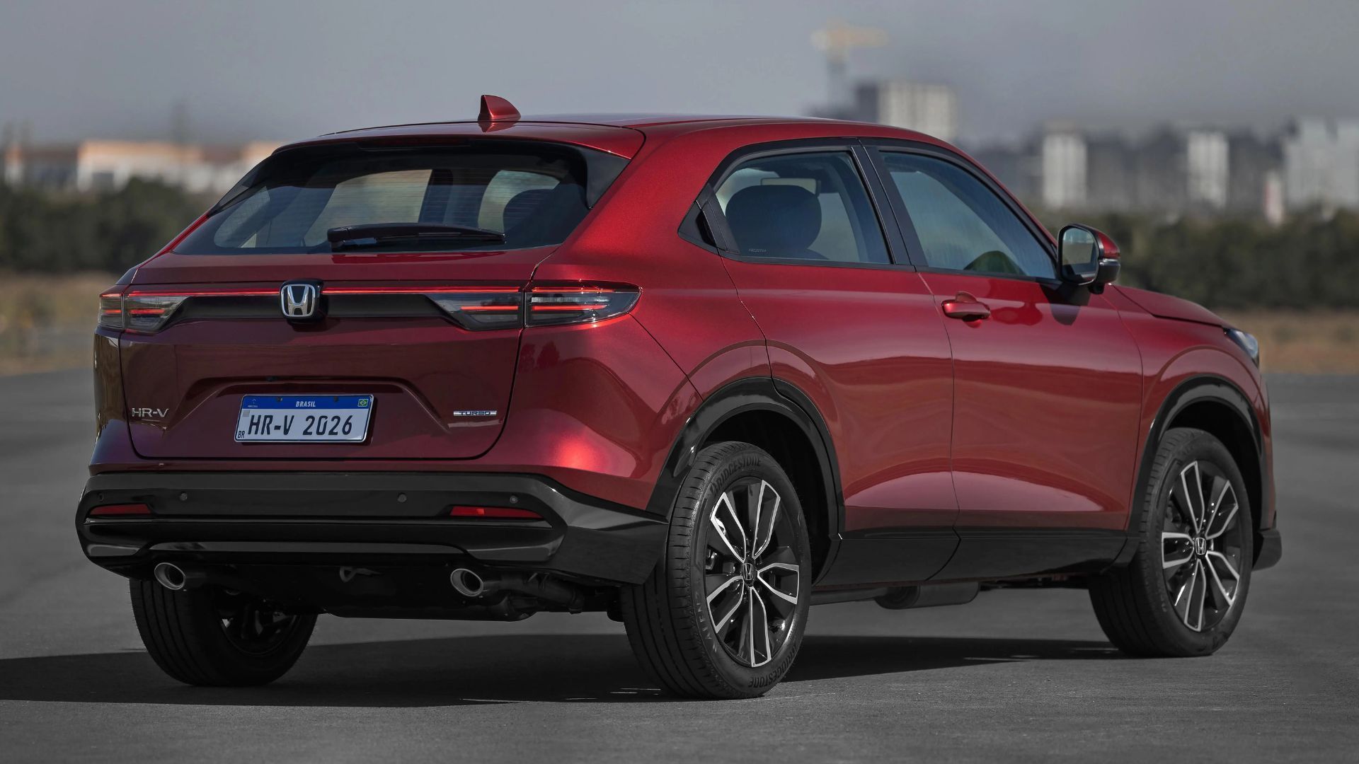 Red SUV seen from the rear three-quarter view on a road, with black trim and tinted windows.