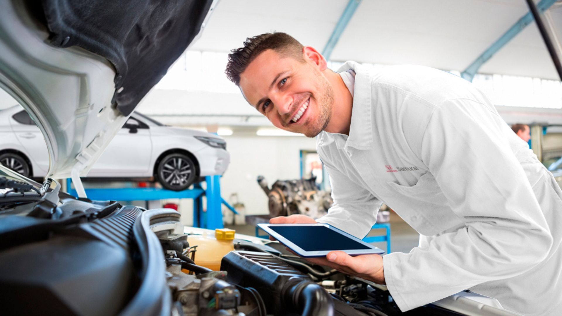 Mechanic smiling beside open car hood in a bright auto repair shop