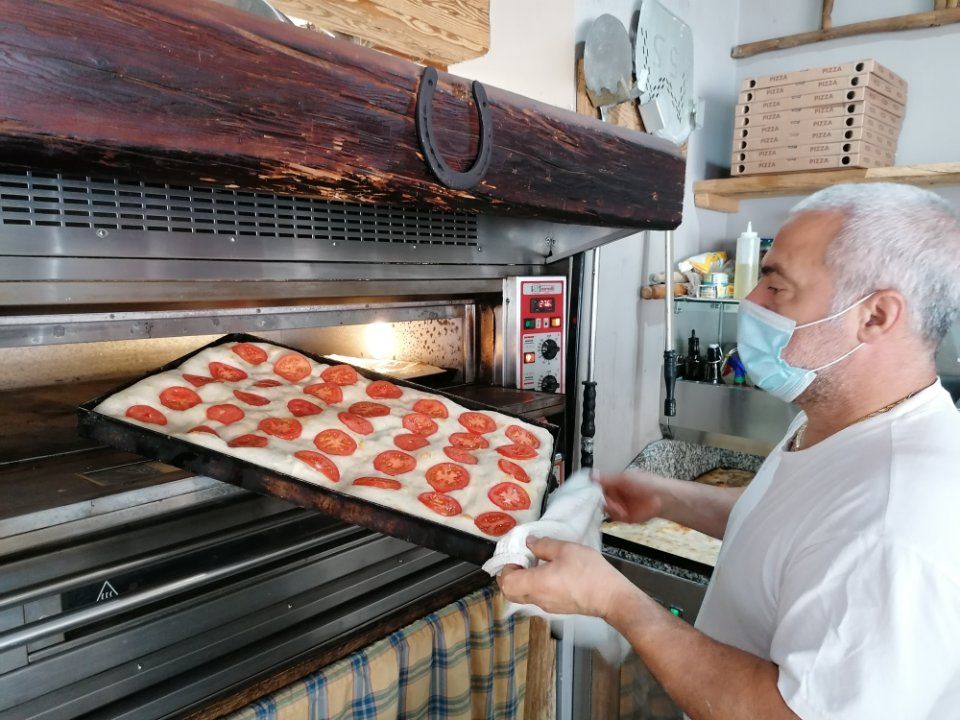 pizzaiolo che informa una pizza in teglia