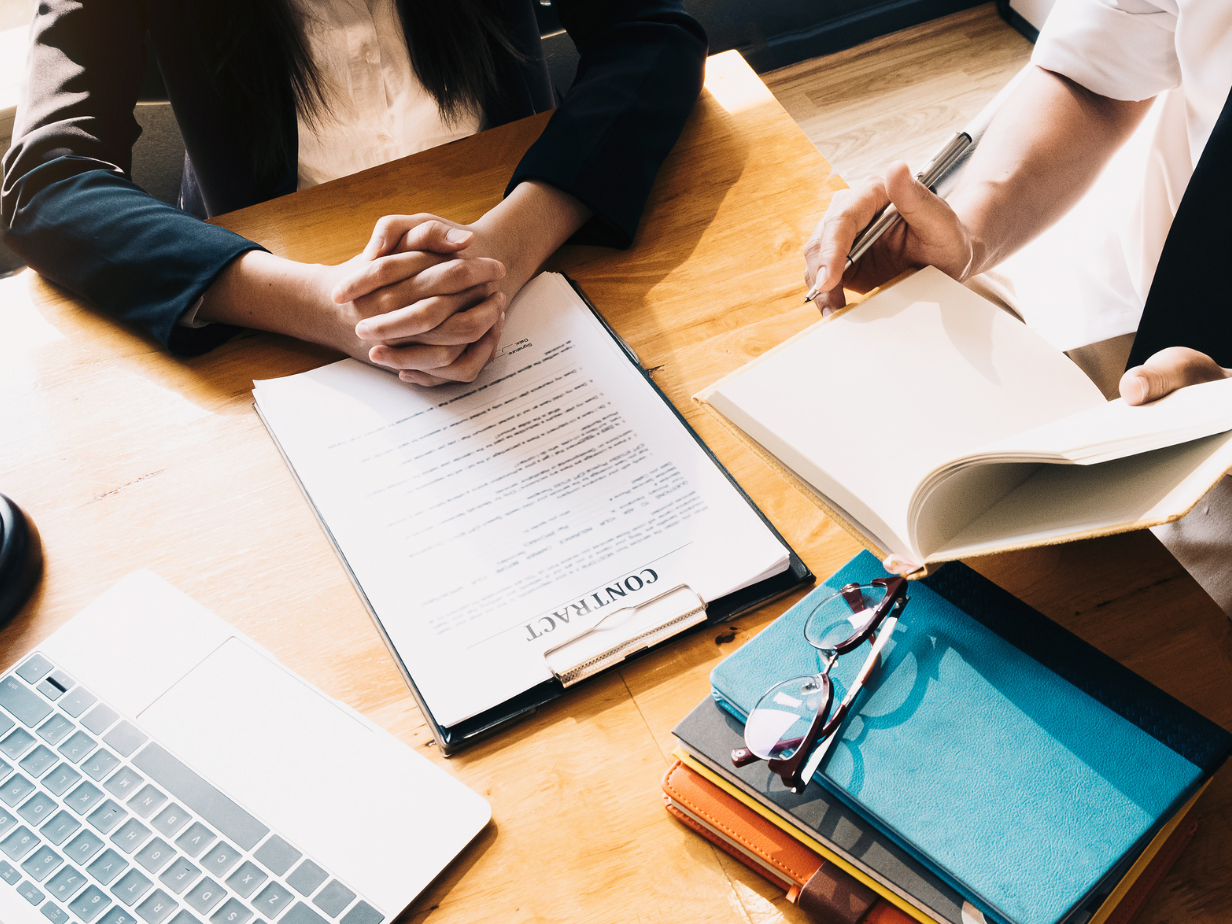 A man and a woman are sitting at a table looking at a contract.