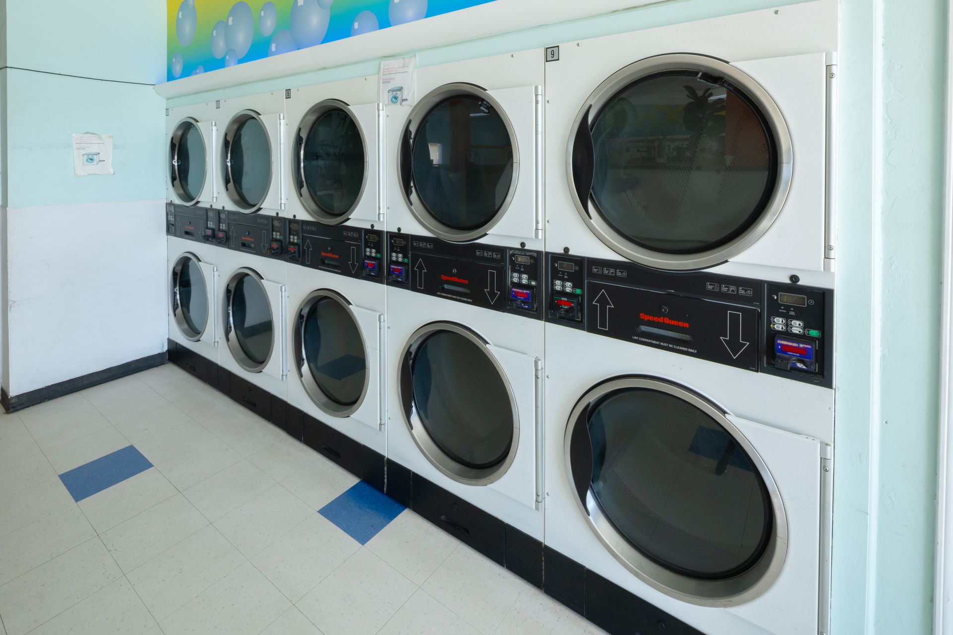 Row of stacked washers and dryers in a bright laundromat