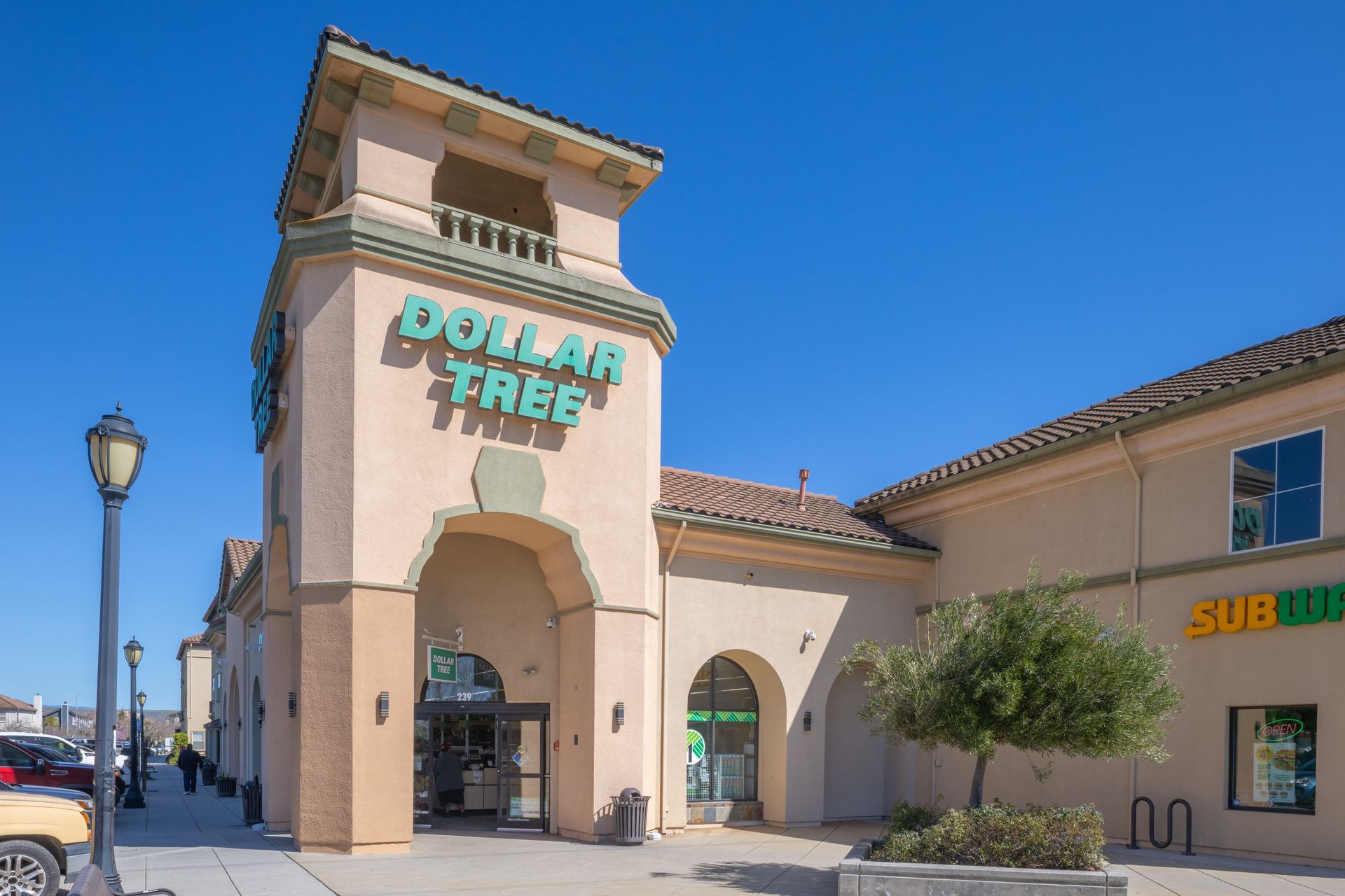 Dollar Tree storefront in a tan shopping center under a bright blue sky