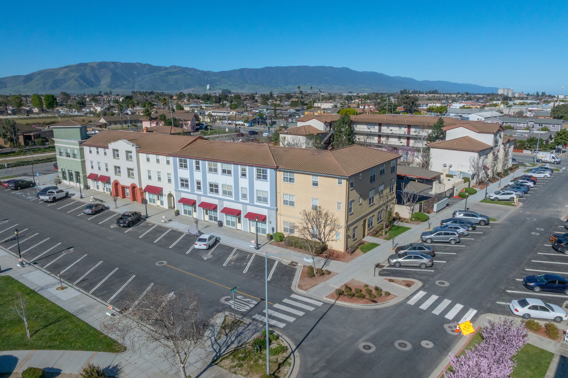 Aerial view of buildings with parking lot, crosswalks, and hills in the background