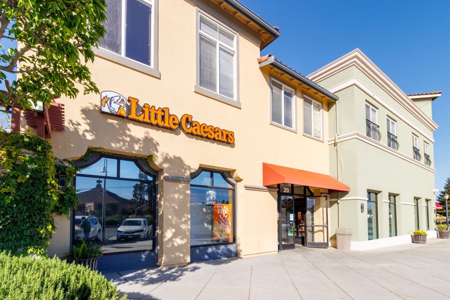 Street-facing storefronts with cream facades, orange awning, and clear blue sky