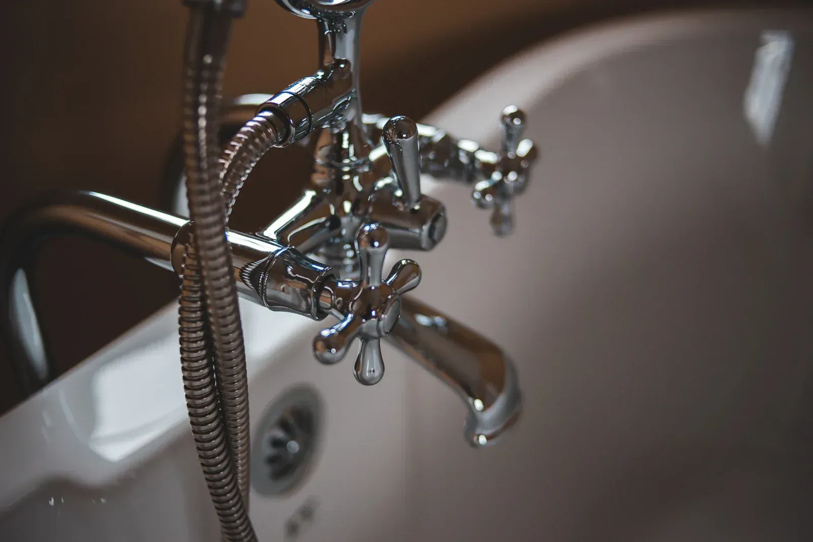 Chrome faucet and showerhead over a white bathtub.