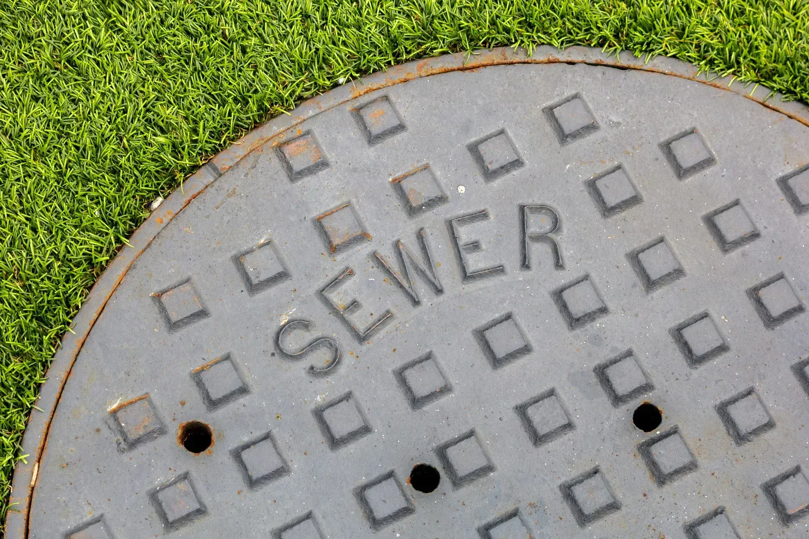 Close-up of a gray sewer manhole cover with the word