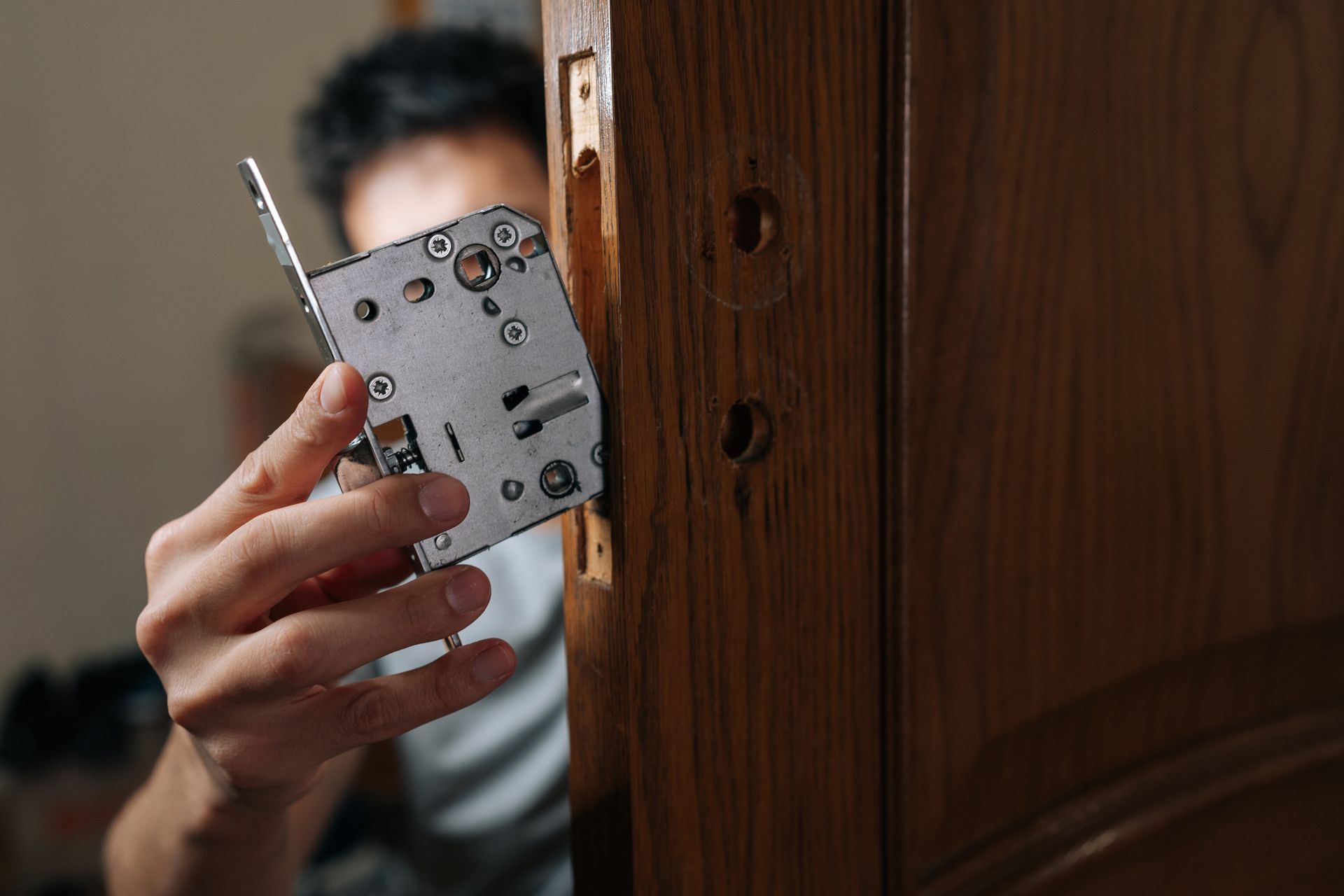 Security technician installing a mortise lock into a wooden door during a residential security system installation