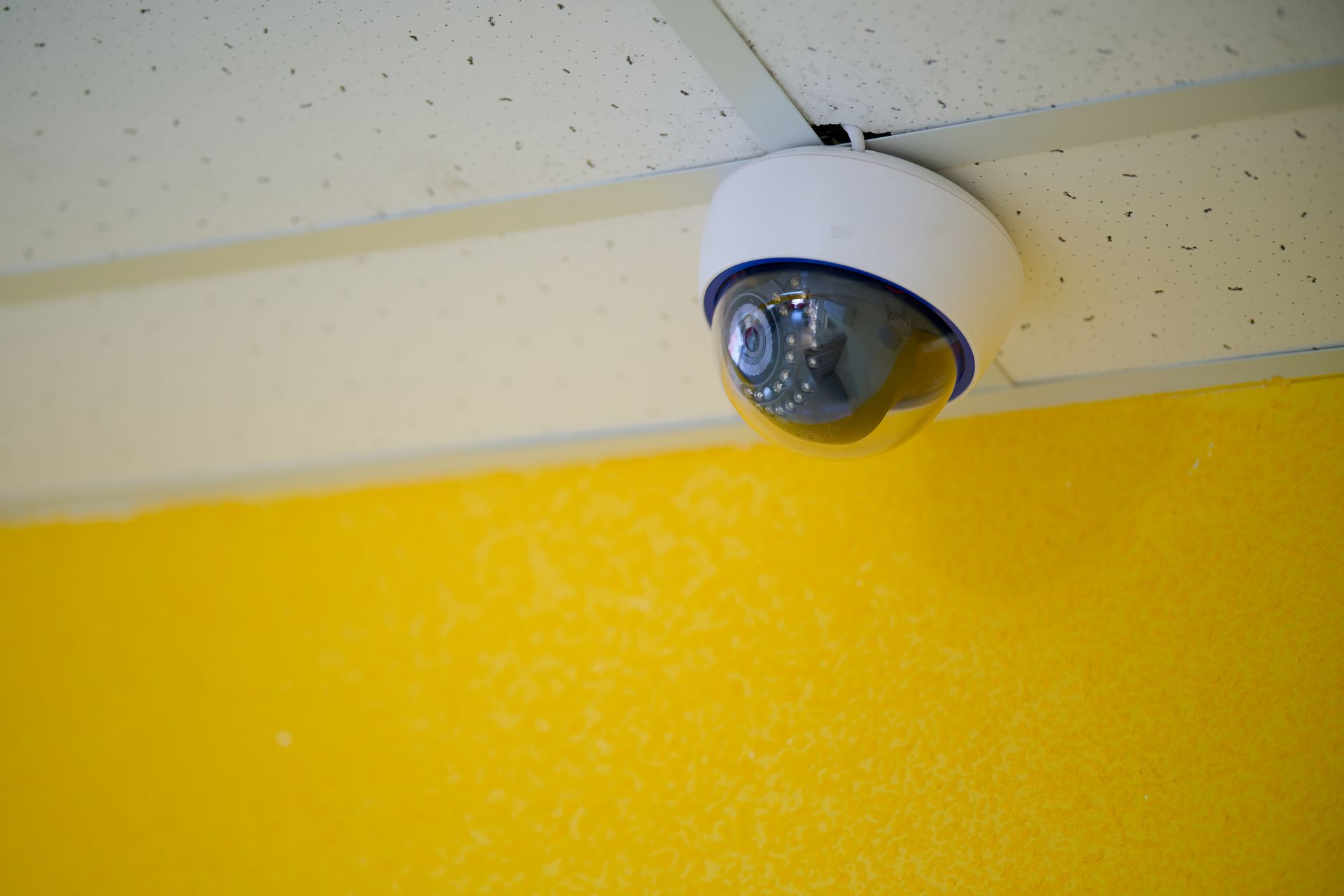 Modern rotating security camera installed on a drop ceiling.
