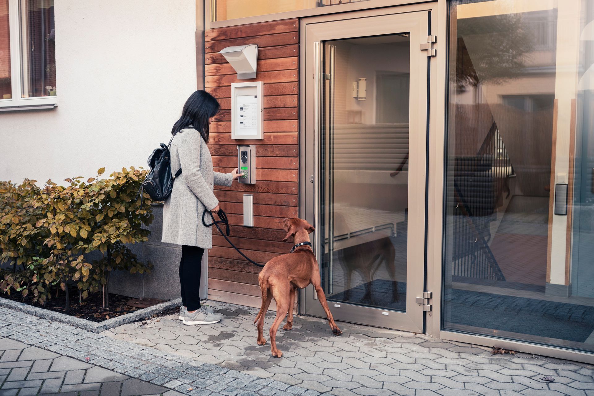 Commercial security system installer setting up keypad entry at modern office building entrance.