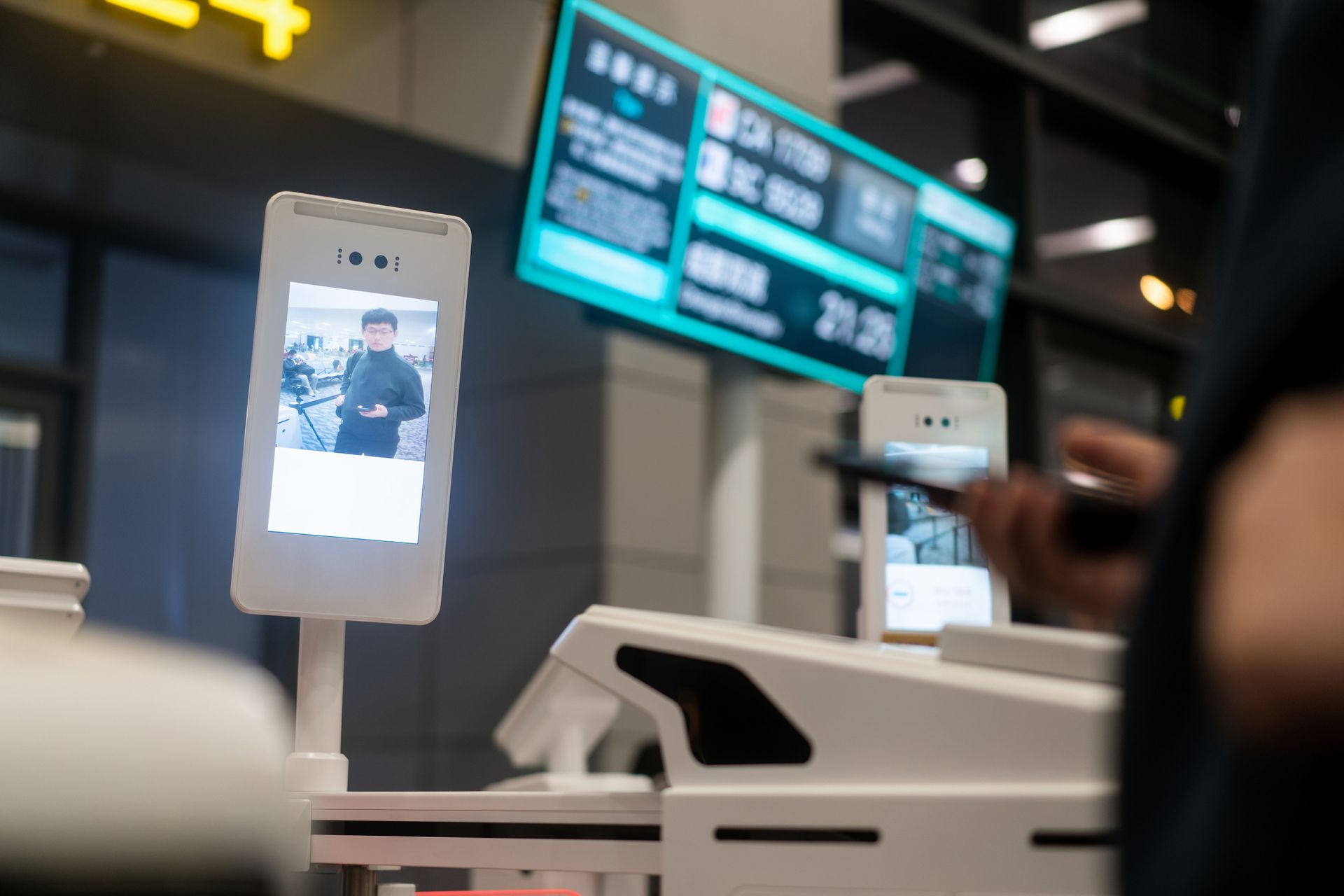 Local security system installer setting up facial recognition terminal at modern facility entrance. Local security system installer setting up facial recognition terminal at modern facility entrance.