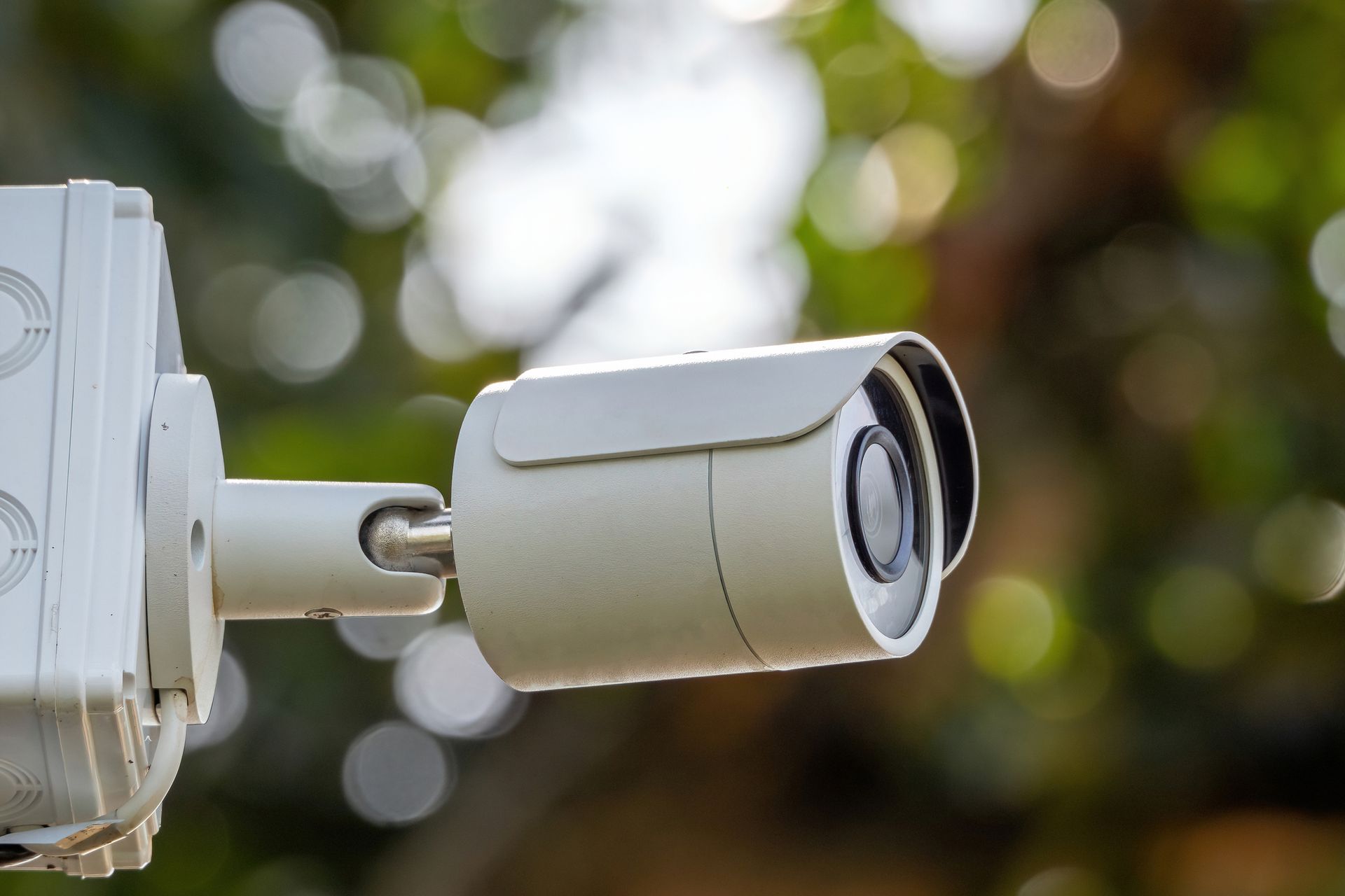 Outdoor security camera mounted on wall with weatherproof casing for home surveillance systems CCTVs.