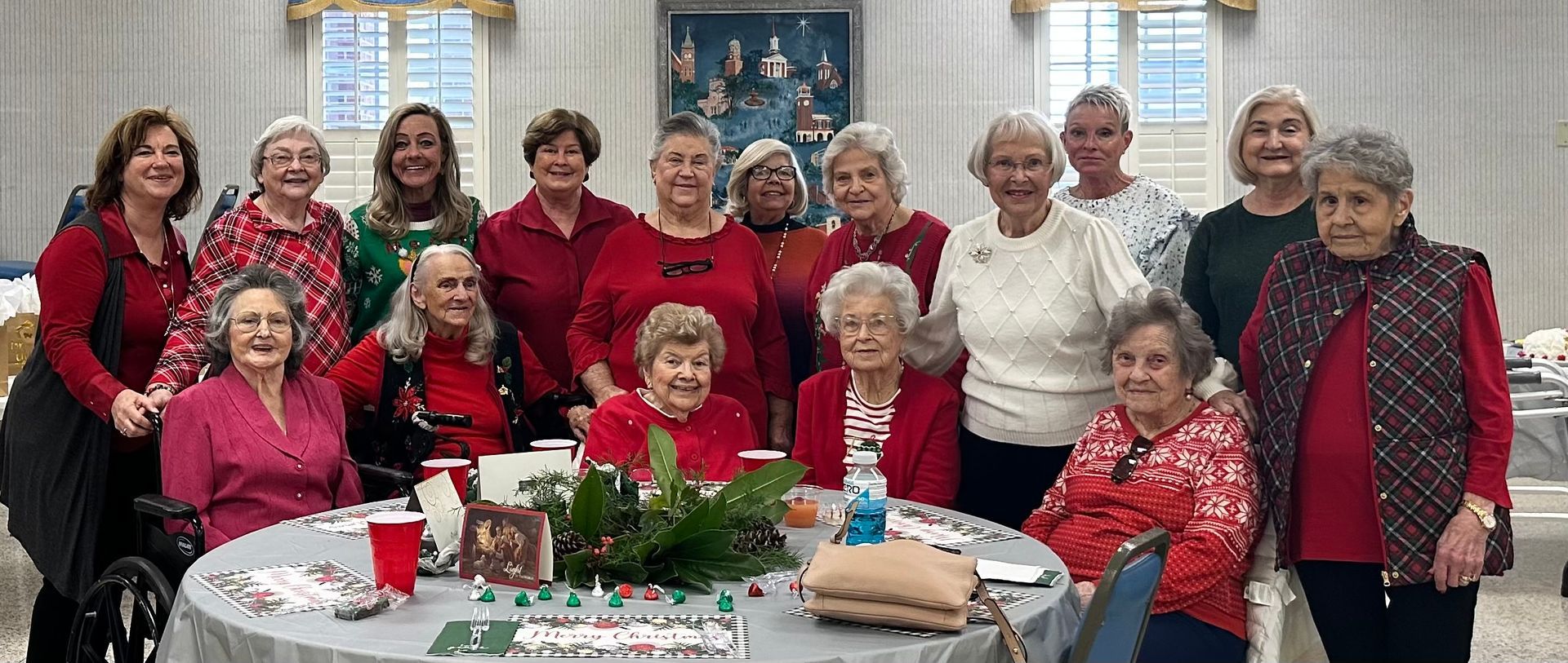 Group of people in red and white outfits smiling around a decorated table indoors