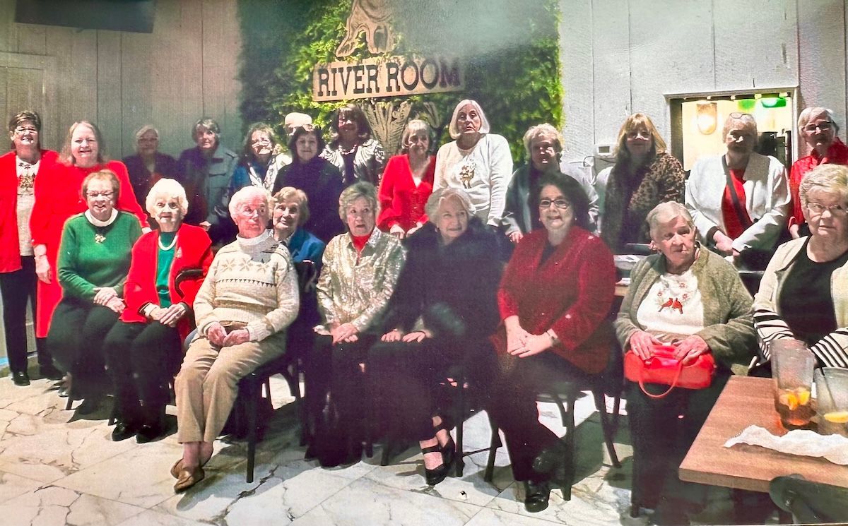 Group of people in red and white outfits smiling around a decorated table indoors